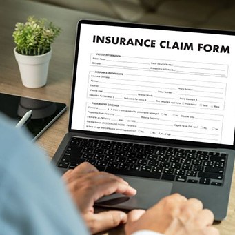 Person filling out insurance claim form on laptop