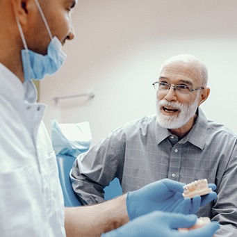 An older man talking to his dentist about dentures