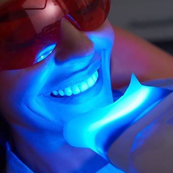 A smiling woman receiving in-office teeth whitening treatment