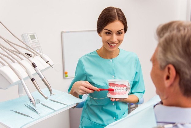 dentist smiling and holding dentures 